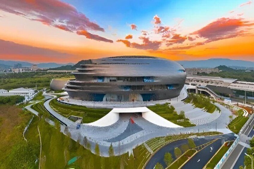 A modern architectural building with a circular design, surrounded by landscaped areas and roads. 1