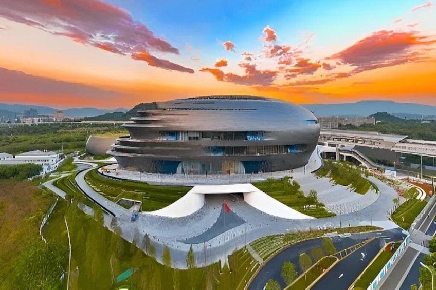 A modern architectural building with a unique circular design, surrounded by landscaped areas and a road network. 1
