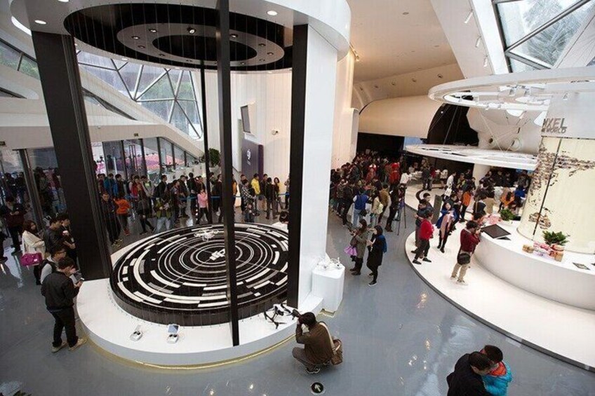 A modern indoor space with a circular black and white design, glass ceiling, and people walking around. 4