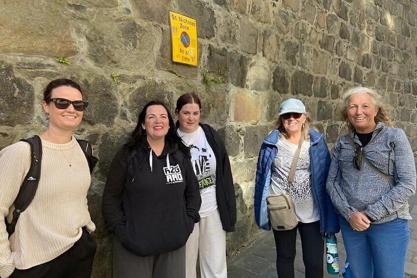 Eine Gruppe von Personen steht vor einer Steinsäule mit einem gelben Schild. 2