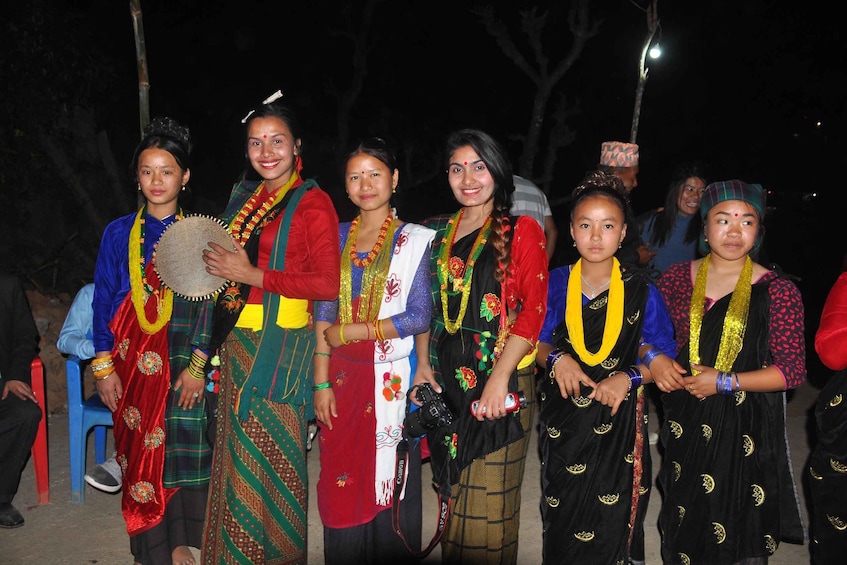 A group of people in traditional attire standing outdoors at night. 5