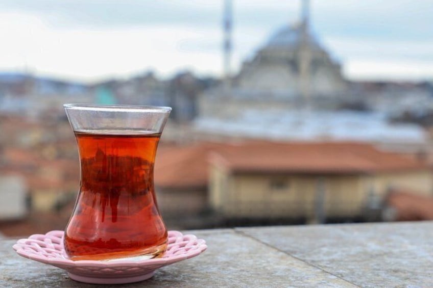 A glass of tea on a pink coaster with a cityscape in the background. 5
