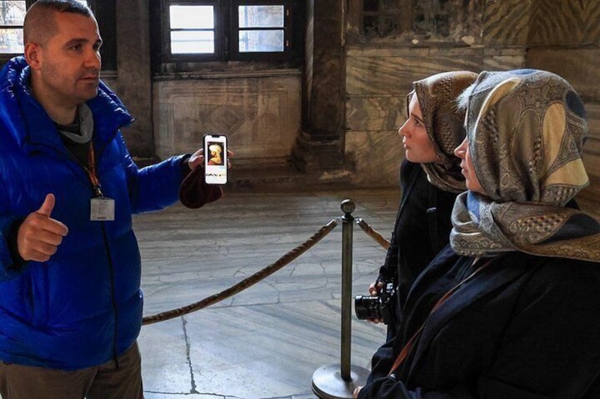 A person taking a photo with a smartphone, a rope barrier, and a stone floor. 1