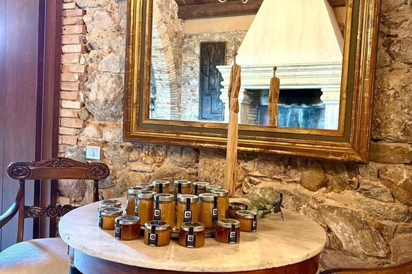A table with jars of preserves, a wooden chair, a stone wall, and a framed mirror. 2