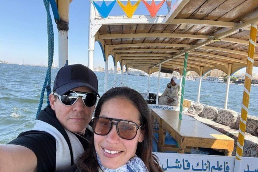 A boat with a covered deck, a person wearing a cap, and a sign with Arabic text. 2