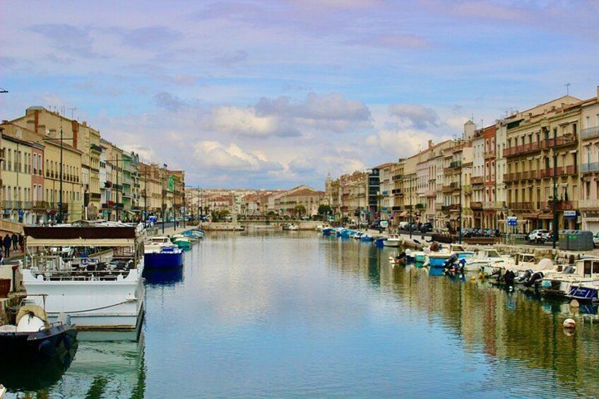 A canal with boats docked on both sides, surrounded by multi-story buildings. 1