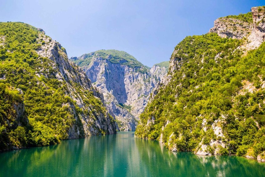 A serene valley with a clear lake surrounded by steep, forested cliffs. 1