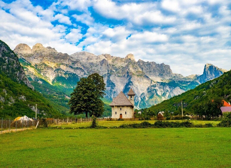 A small church in a valley with mountains in the background. 5