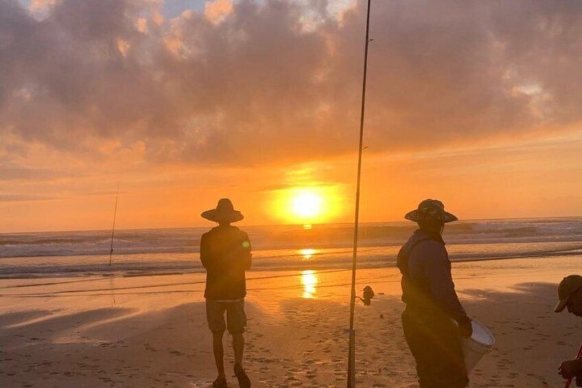 Two people fishing on a beach at sunset. 5