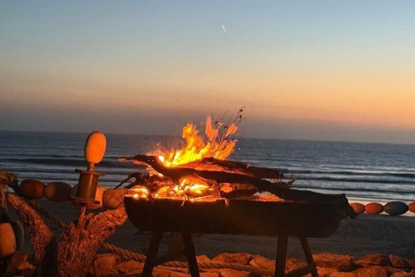 A campfire on a beach with the ocean in the background. 2