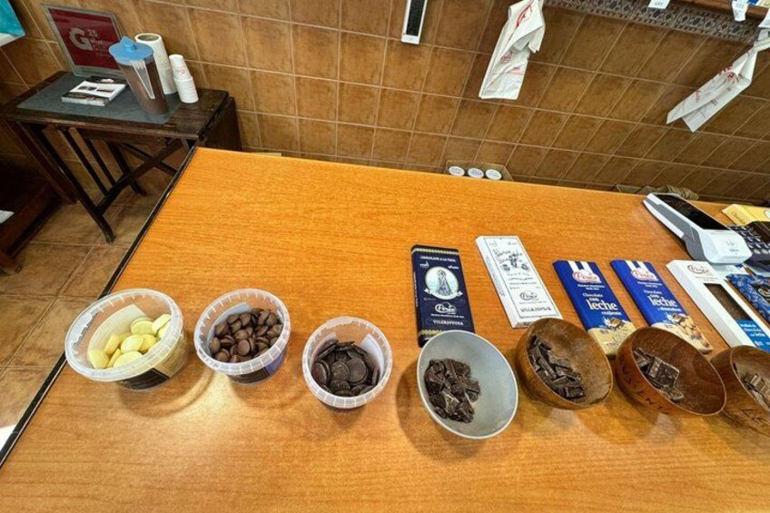 Un tavolo con diversi cibi e imballaggi, tra cui ciotole di noci e cioccolato, e scatole di barrette al cioccolato. 2