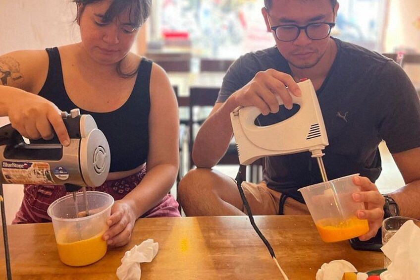 Deux personnes sont assises à une table : l’une verse du jus d’orange d’un emballage dans une tasse, et l’autre fait de même. 4