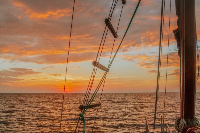 Un atardecer sobre el océano, con la aparejo de un velero y un mástil de madera. 2