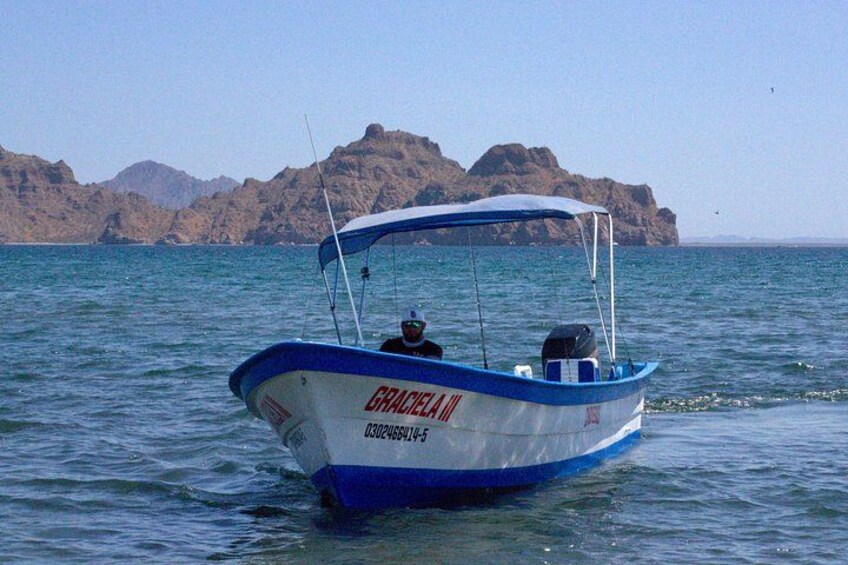 Una embarcación llamada 'GRACELLA' sobre aguas tranquilas, con colinas rocosas al fondo. 5