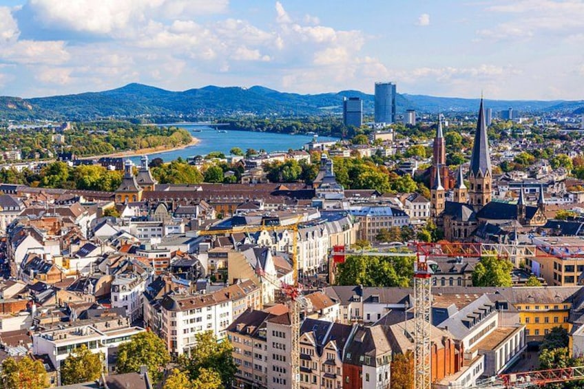 A cityscape with a prominent church spire, a river, and a mountain range in the background. 5
