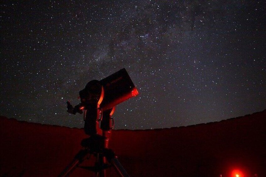 Un télescope installé sur un trépied, pointé vers un ciel nocturne constellé d’étoiles. 2