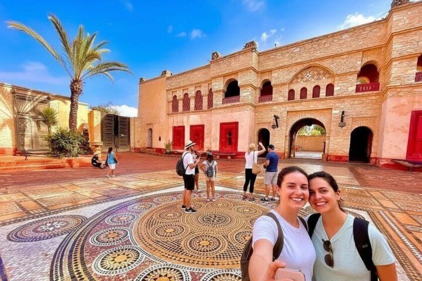 Un cortile con pavimento decorato, un edificio con porte rosse e palme. 1