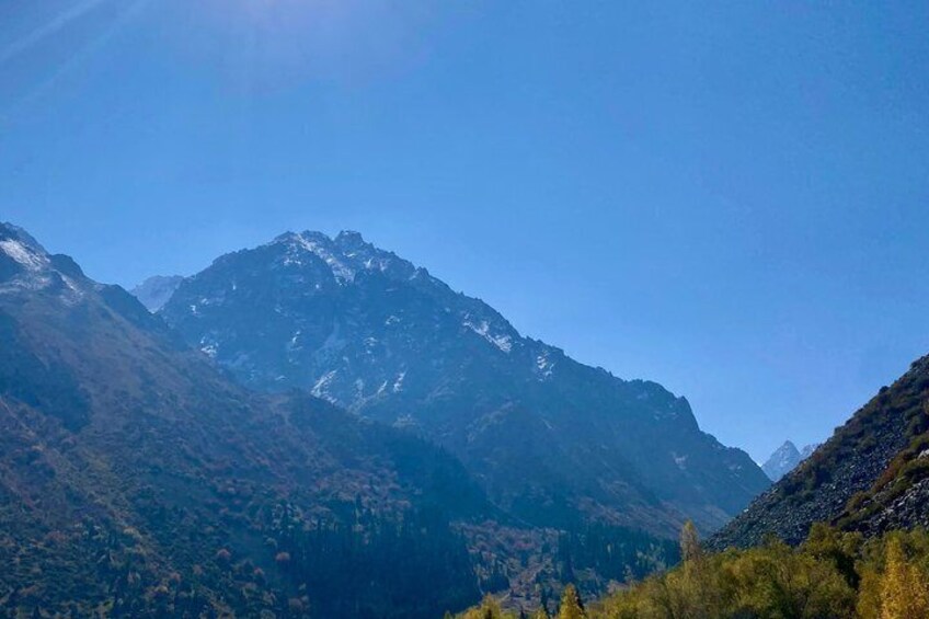 A mountain range with snow-capped peaks and dense forested valleys. 2