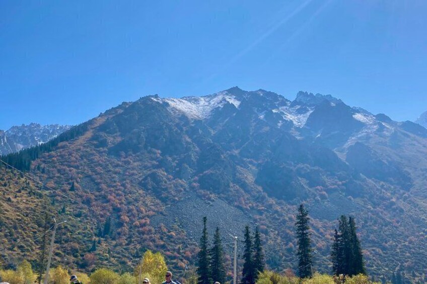 A mountain range with snow-capped peaks and autumn-colored trees. 3