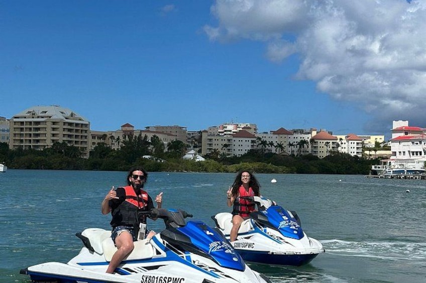 Two people on jet skis with a marina and buildings in the background. 5