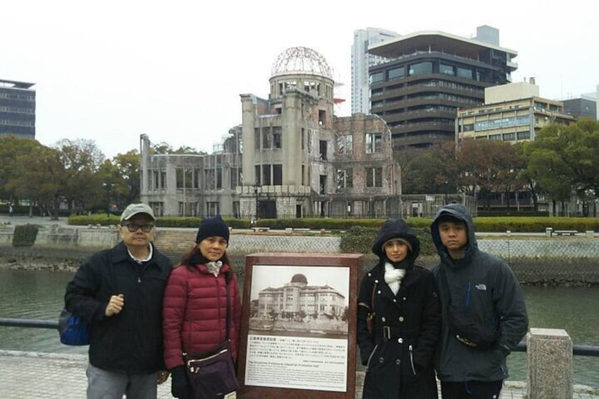 Un grupo de personas frente a un edificio histórico, con un cuerpo de agua y edificios modernos al fondo. 5