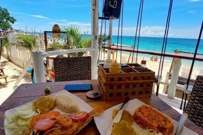 Una mesa con comida, vista al mar y una valla de madera. 3