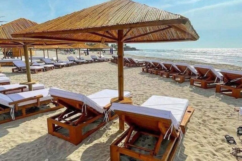 Una playa con sillas de madera y sombrillas de paja. 5