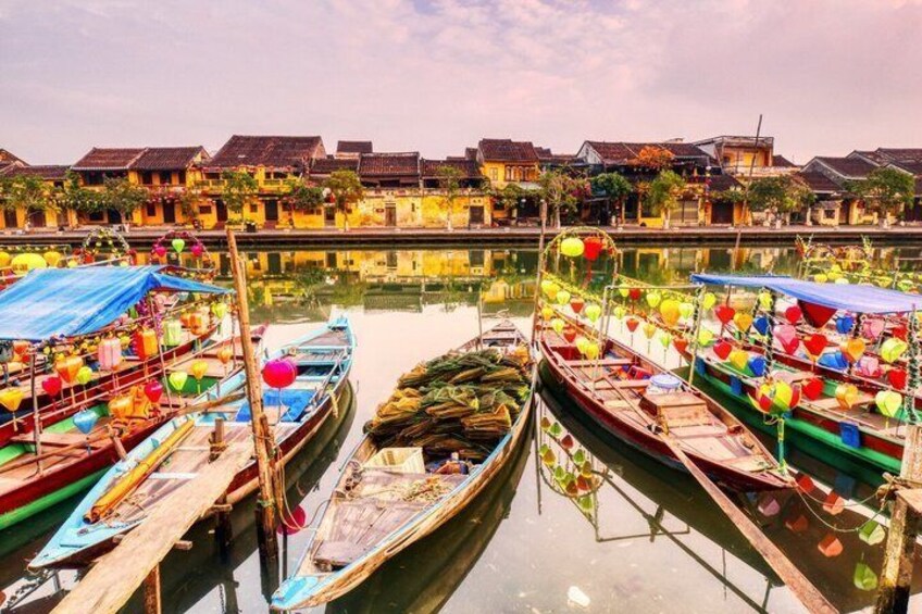 Un canal où sont amarrés des bateaux traditionnels, des maisons en bois en arrière-plan et un ciel dégagé. 4