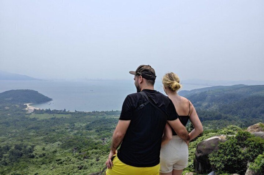 Un couple admire un paysage côtier avec des collines et une plage. 1