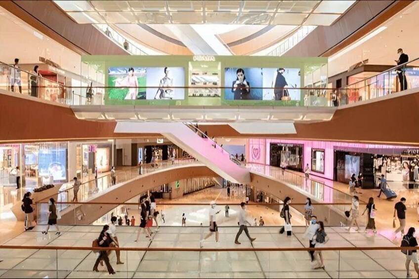 Un centro commerciale a più livelli con scale mobili, negozi e clienti. 5