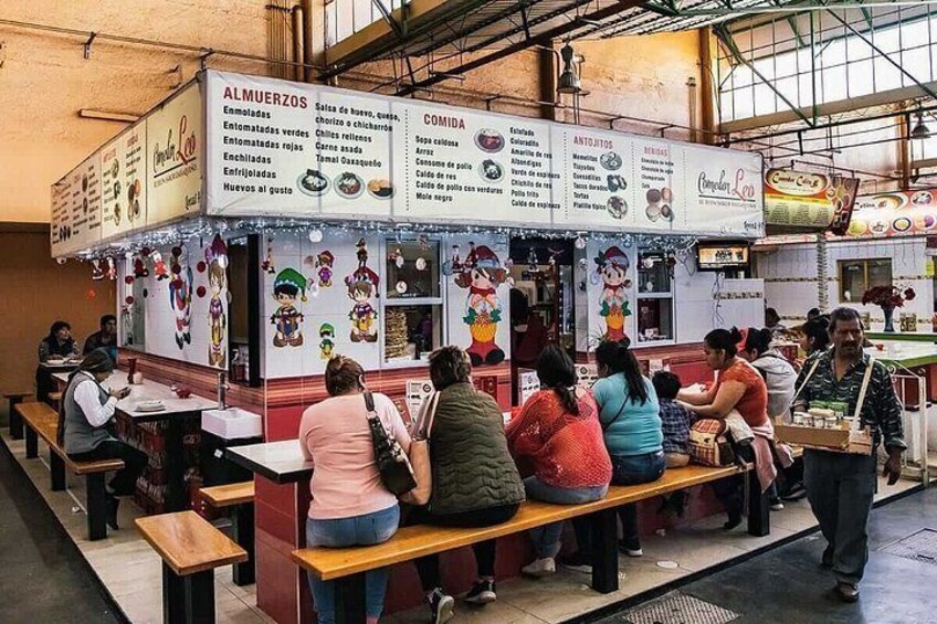 Un espace restauration avec un panneau affichant le menu et des personnes assises à des tables. 4