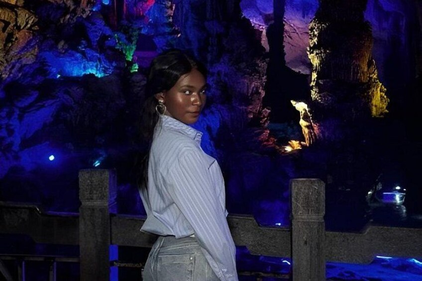 A person standing in front of a cave with illuminated rock formations. 5