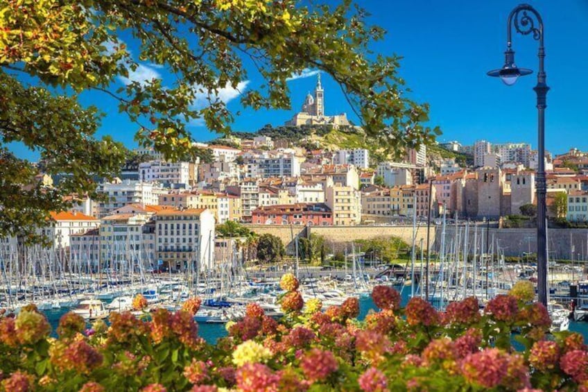 A marina with boats, a cityscape with historic buildings, and a hilltop landmark. 1