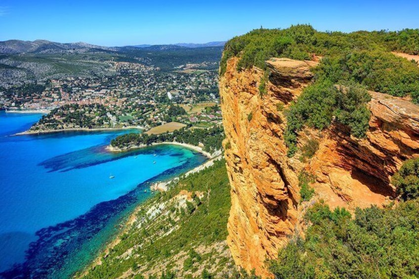 A coastal town with a prominent cliff, clear blue waters, and a hilly landscape. 4