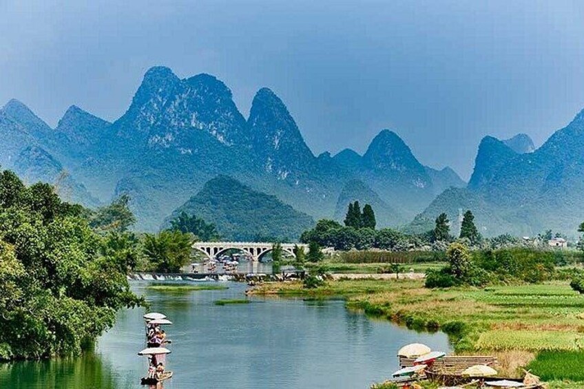 Une rivière avec un pont, des montagnes et un bateau rempli de personnes. 1