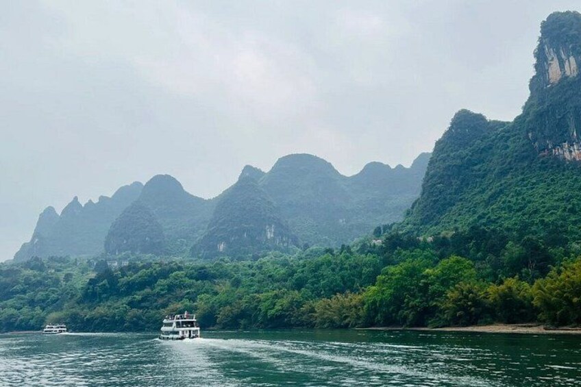 Un bateau sur une rivière, avec des montagnes verdoyantes en arrière-plan. 2