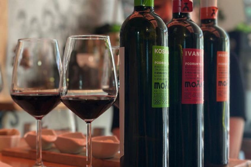 Dos copas de vino tinto y tres botellas de vino con etiquetas. 5