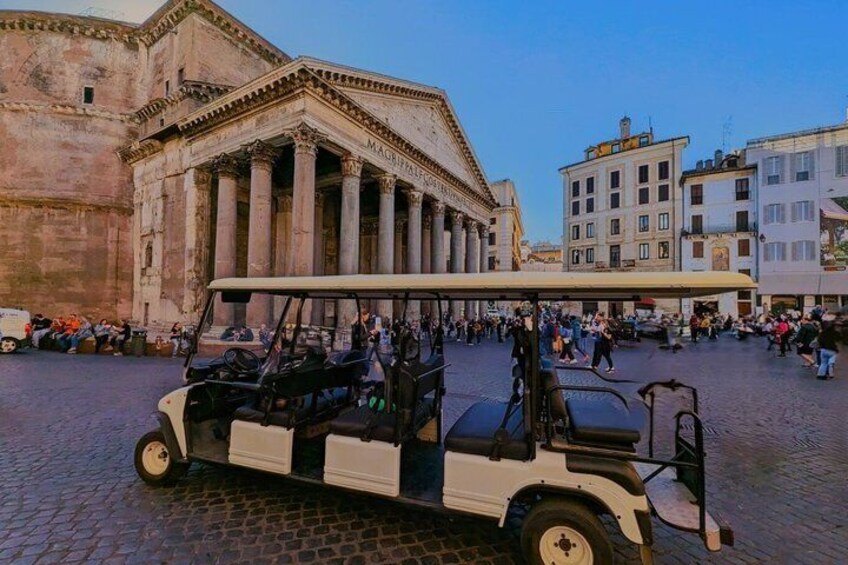 Un carrito de golf en una plaza adoquinada con edificios históricos al fondo. 1