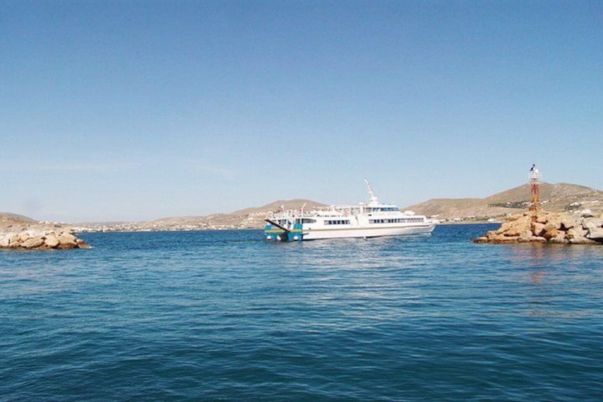 A white boat docked near rocky shores with a lighthouse in the background. 2