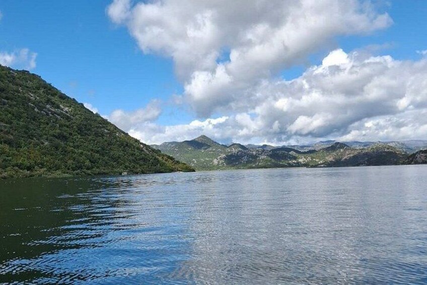 Un lago tranquilo rodeado de colinas verdes bajo un cielo parcialmente nublado. 4