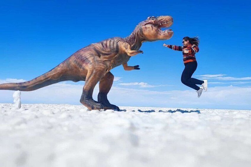A person jumping in front of a dinosaur model. 1