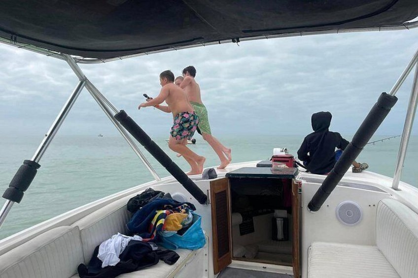 Un bateau avec des personnes sur le pont, une personne qui saute du bateau et un ciel nuageux. 3