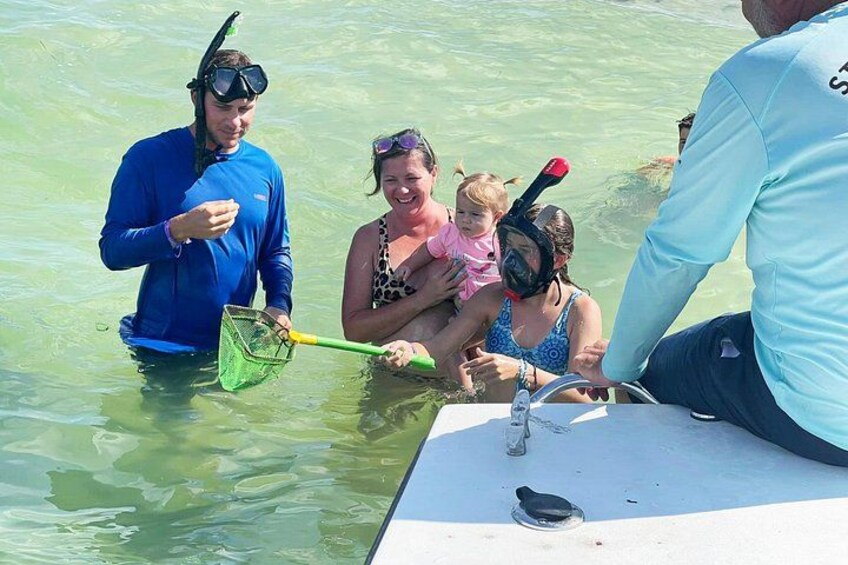 People in a boat, some wearing snorkeling gear, and a child being held by an adult. 3