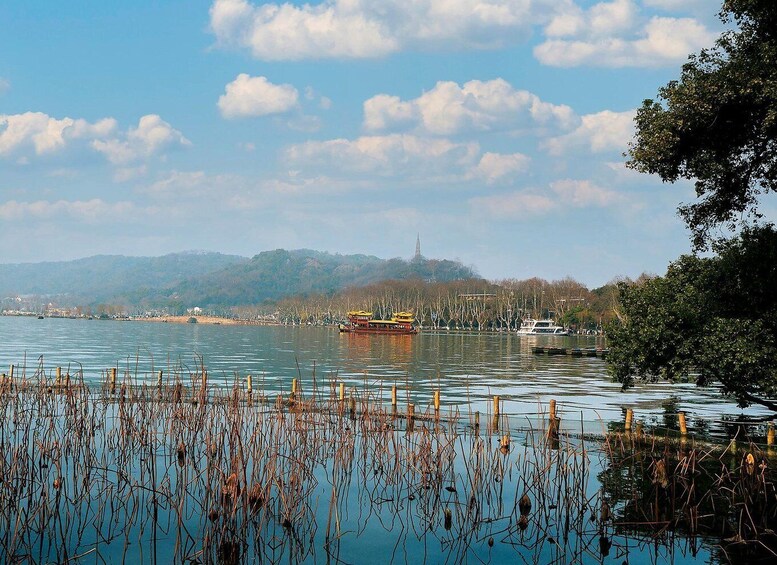 A calm lake with a traditional boat, reeds in the foreground, and a distant hill with a tower. 3