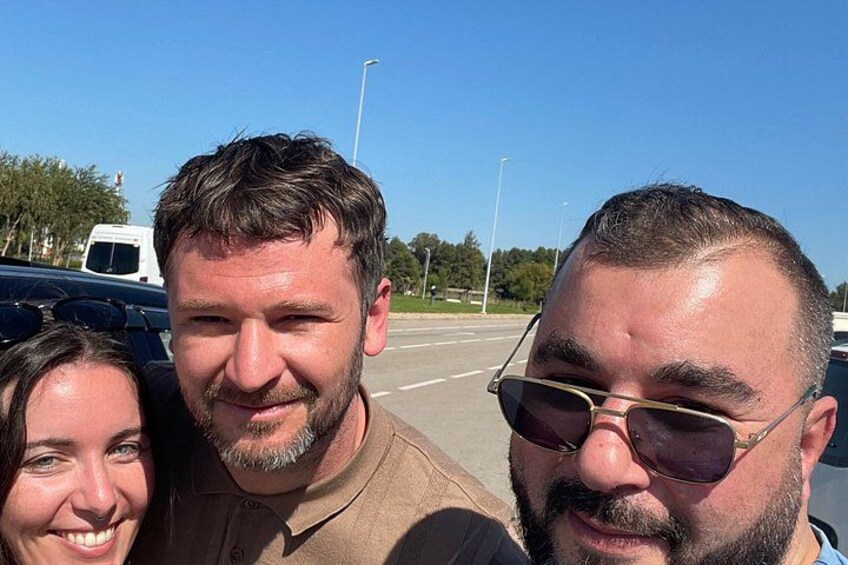 Three people outdoors, a parking lot, and a clear sky. 5