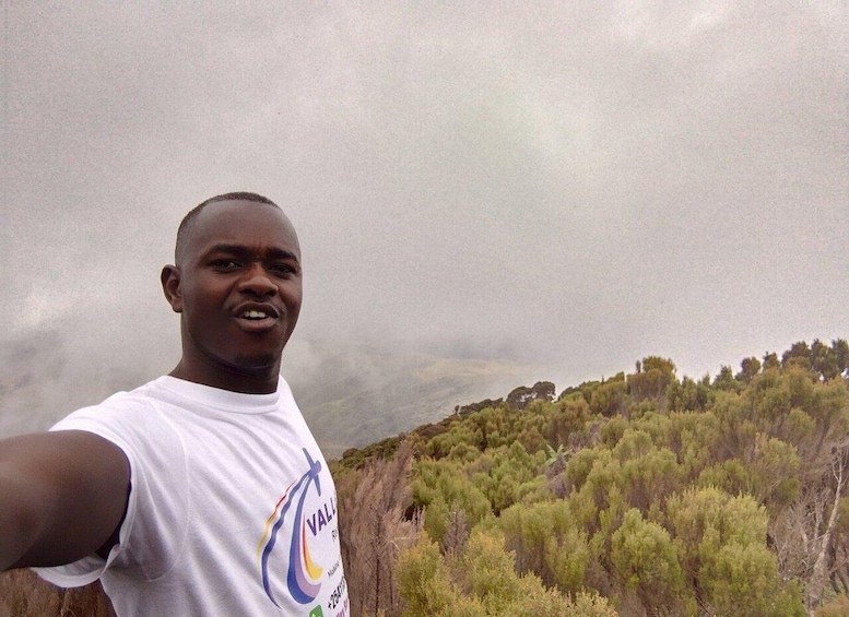 A person taking a selfie with a mountainous landscape in the background. 5