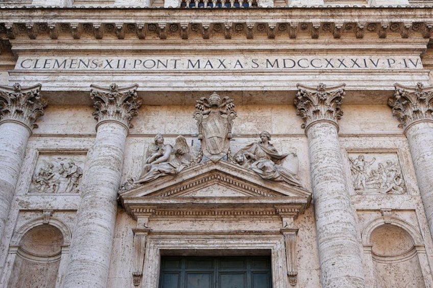 A detailed facade of a historical building with inscriptions, columns, and classical sculptures. 1