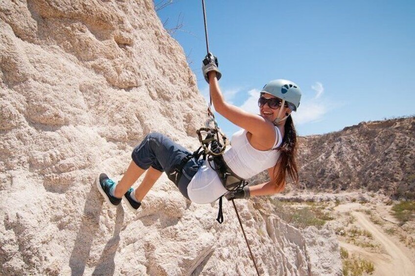 A person rock climbing on a sandy cliff with a clear sky in the background. 3