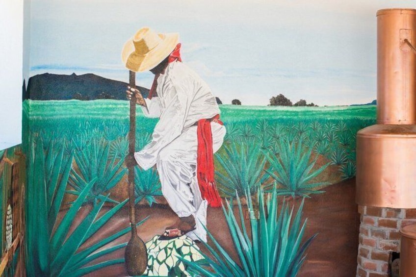 A mural of a person in traditional attire working in a field with a large copper structure nearby. 2
