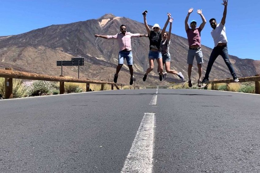 A group of people jumping on a road with a mountainous landscape in the background. 4